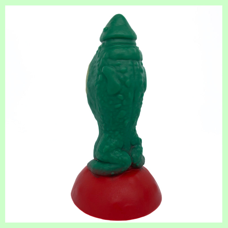 Toady Stool dildo rear view. Toad-themed dildo with a green body and wart texture, on a red toad stool perch