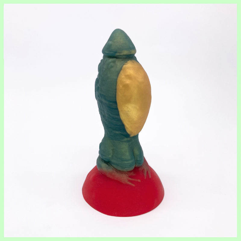 Toad dildo in green with large round gold belly, sitting on a red toadstool base